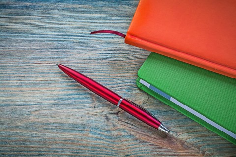 Set of closed notepads ballpoint pen on vintage wooden board office concept