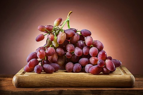 Rose grape on wooden cutting board and brown gradient background