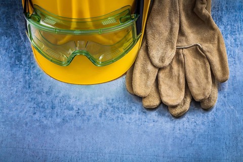 Safety leather gloves hard hat and multiple-purpose protective glasses on scratched metallic