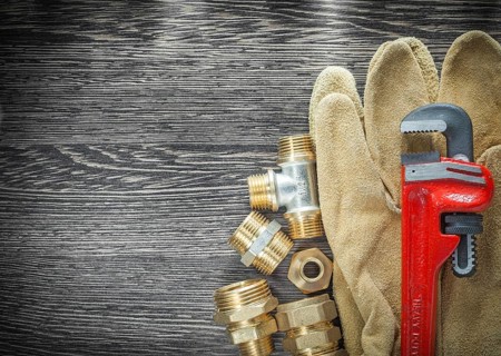 Plumbing pipe wrench fittings safety gloves on wooden board