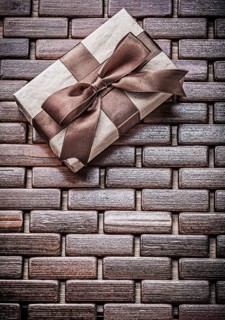 Wrapped present with ribbon on wooden wicker matting holidays concept
