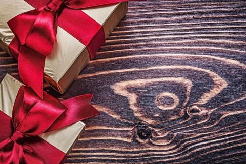 Wrapped gift boxes with red satin ribbons on wood board