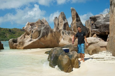 Seychelles island Curieuse with the famous granite rocks and man with caught fish