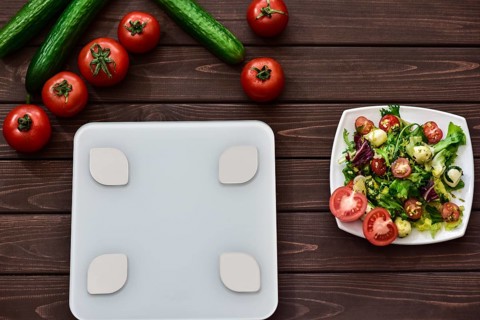 Dieting and control calories for good health concept. salad. smart weight scales. veggies on board.