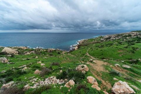 View over a green landscape with rocks and the Mediterranean sea in the background in Selmun,
