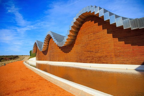 Wave-shaped winery roof. Fragment of the facade is reflected in the pool. Winery - bodega Bodegas