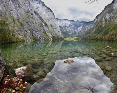 Magic reflection in German lake Koenigssee. Cloudy day on the lake. Clouds and mountains reflected
