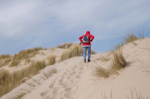 Hiker walking up a sand dune at the beach on a sunny day