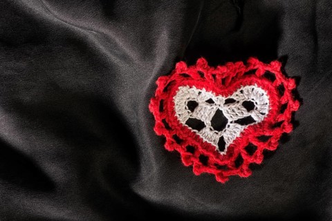 Heart shape made of red textile on black satin