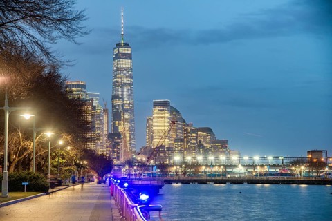 Downtown Manhattan night skyline from Hudson River Park. Skyscrapers lights and city pier
