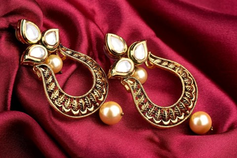 Beautiful Golden pair of earrings Diamonds gemstones on a red satin background. Luxury female