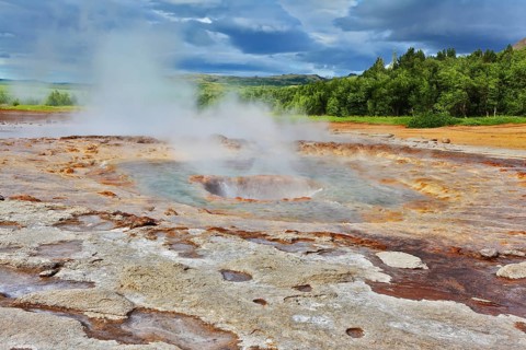 Fumaroles Geyser Strokkur. Water vapor from the crater geyser under bizarre clouds. Summer Iceland