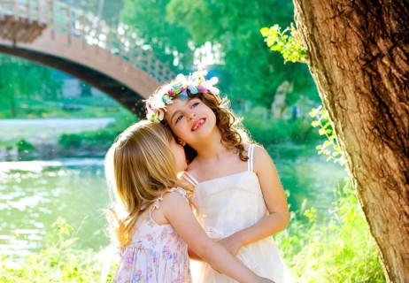 Kid girls playing in spring outdoor river park whispering ear
