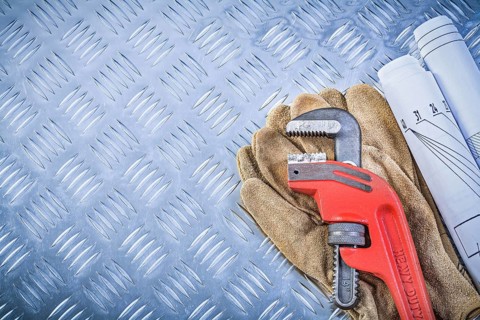 Monkey wrench blueprints leather protective gloves on grooved metal background construction concept