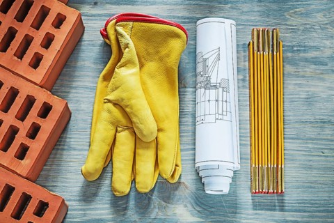 Red bricks leather safety gloves wooden meter construction drawings building concept