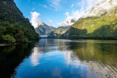 A new morning dawning at Doutful Sound, clouds hanging low in the mountains, South Island of New
