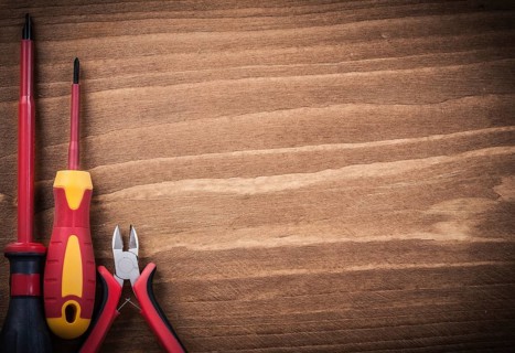 Sharp nippers insulated screwdrivers on wooden board copyspace electricity concept