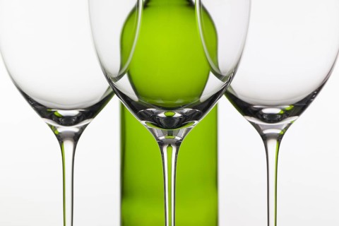 Three empty glasses of wine and green bottle on the white background