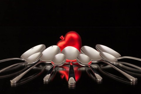 Nine spoons and red heart on a black glass desk