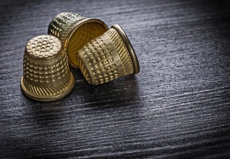 Metal thimbles on wooden board fancy-work concept