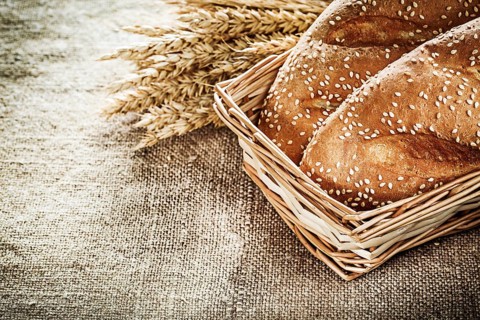 Wicker basket bread rye ears on burlap background