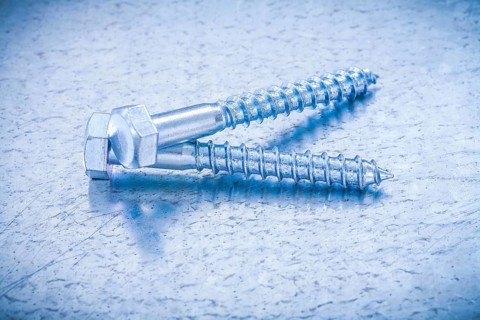 Pair of threaded screw bolts on metallic background construction concept