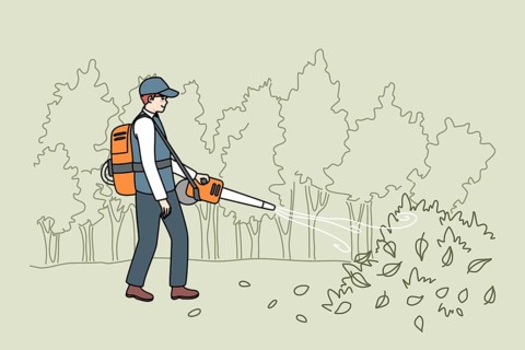 Male gardener in uniform collection leaves with handy vacuum. Man handyman working outdoors in