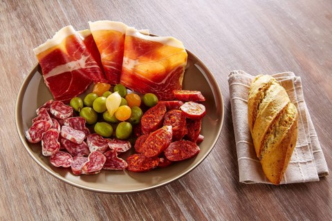 Tapas of Spain with ham bread olives sausage and chorizo on wooden background
