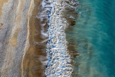 Aerial view of stormy ocean waves breaking on a sandy beach. Nature background