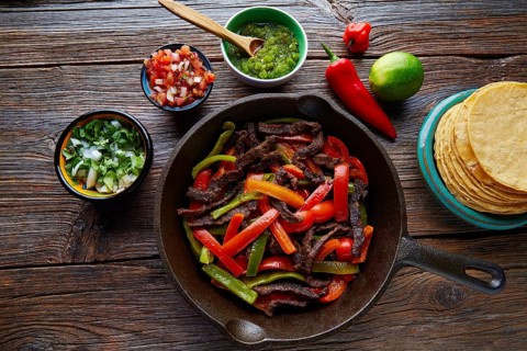 Beef fajitas in a pan with sauces chili and sides Mexican food