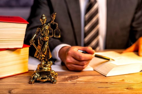 Office of a lawyer with books and a statue of Lady Justice, goddess Justitia, on the desk