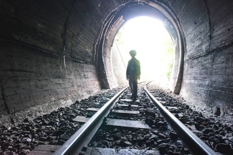 Child walking in railway tunnel. Vintage clothes
