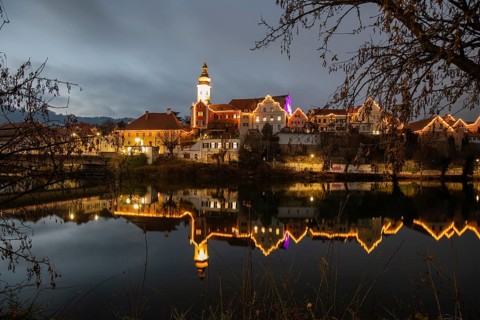 Christmas illuminated house facade of Frohnleiten reflected in the river Mur, Frohnleiten, Styria,