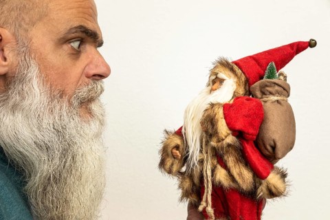 An image of a bearded man looking to a Santa Claus puppet