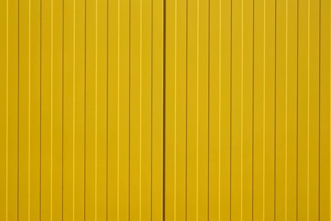 The close-up of a colourful and bright yellow corrugated metal wall of a shopping centre