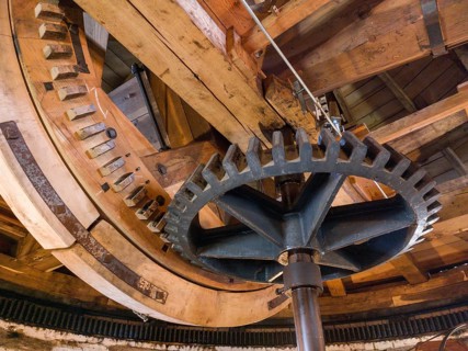 Large cogwheels within an old wooden structure, industrial mechanics visible