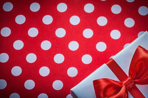 White present box with knot on polka-dot red fabric holidays concept