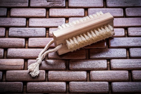 Wood peeling brush on textured wooden matting close up view healthcare concept