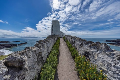 Twr Mawr Lighthouse, white lighthouse by the sea with blue sky and clouds, Ynys Llanddwyn,