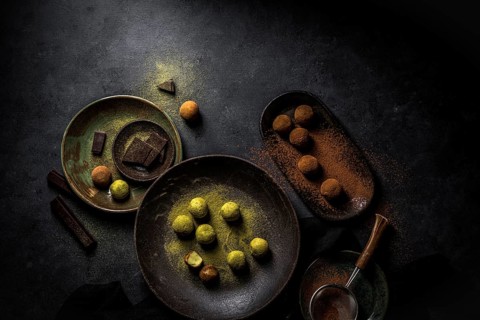 Overhead big plate with green truffle Matcha and plate with brown truffles balls with powder and