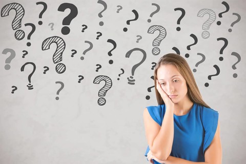 Bored and sad woman with lots of doubts and question marks around her