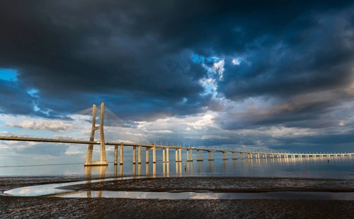 Vasco da Gama Bridge at sunset with dramatic cloudy blue sky in Lisbon, Portugal, Europe