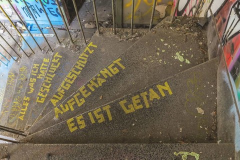 Graffiti-covered staircase with yellow text: Everything I had swallowed, slashed, hung up, it's
