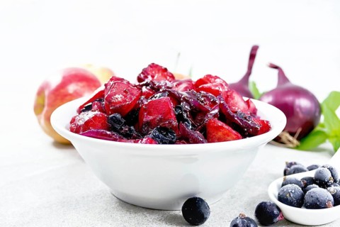 Chutney of apple, red onion and blackcurrant in a bowl against a granite countertop