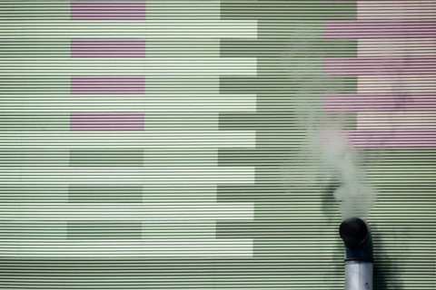 The smoking chimney of an industrial plant on the outer wall of a power station