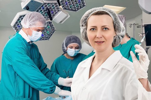 Adult female anesthetist with syringe on the surgery teem background