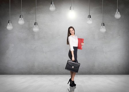 Business woman stnads in a gray room with hanging bulbs