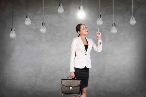 Business woman stands in a gray room with hanging bulbs
