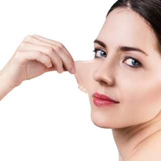 Beautiful woman remove her old dry skin from face. Over gray background