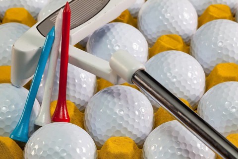 White golf balls in the yellow box and golf equipments